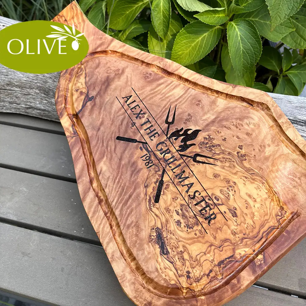Motiv THE GRILLMASTER - Mediterranes Schneidebrett aus Olivenholz mit handgriff und Saftrille und personalisierten Gravurmotiv - Jeske Design