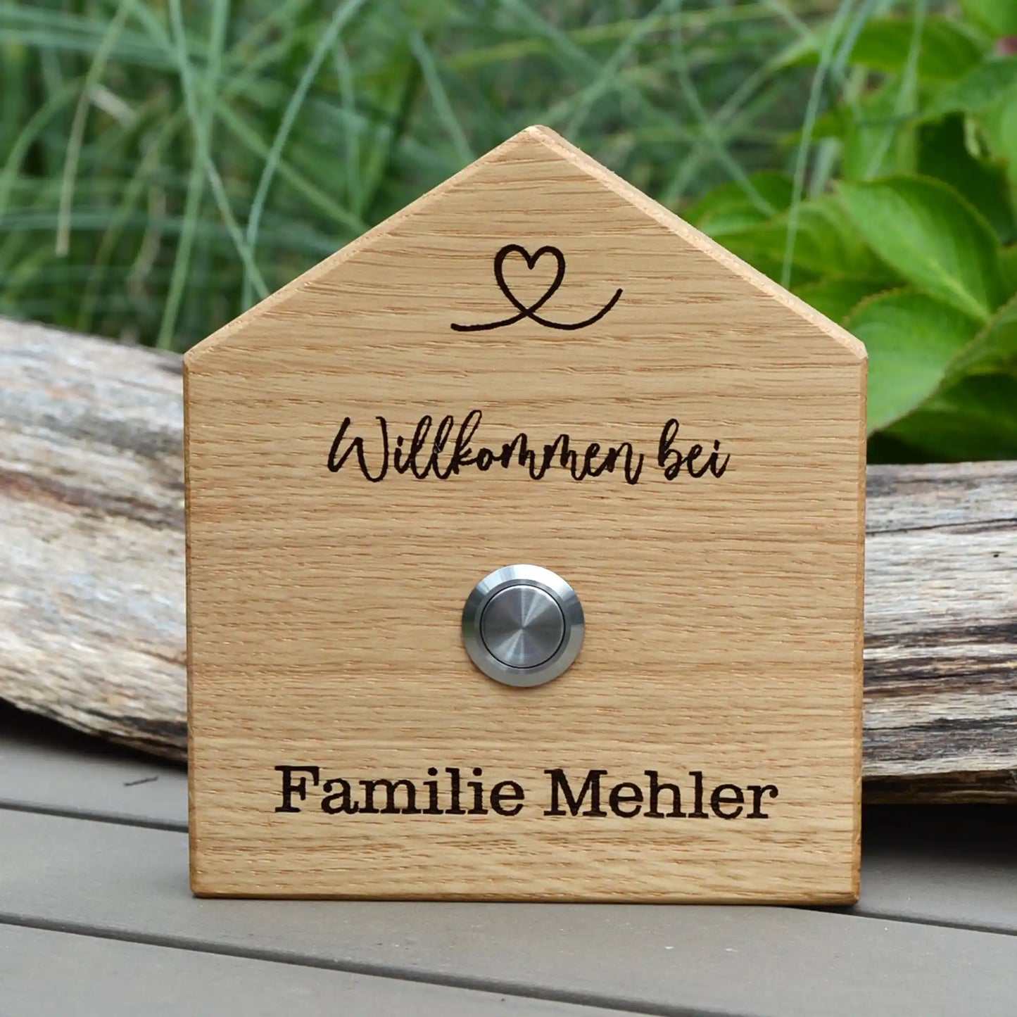 Klingelschild in Hausform aus edler Eiche mit Auswahl eines unbeleuchteten Tasters, LED-Taster oder schwarz-Aluminium-Taster in der Größe 12 x 14 cm oder 14 x 25 cm. Name wird per Laser in das Holz graviert. Mit einem geschwungenem Herz in der Dachspitze und in geschwungener Schrift "Willkommen bei" und unterhalb des Tasters "Familie" und der Nachname