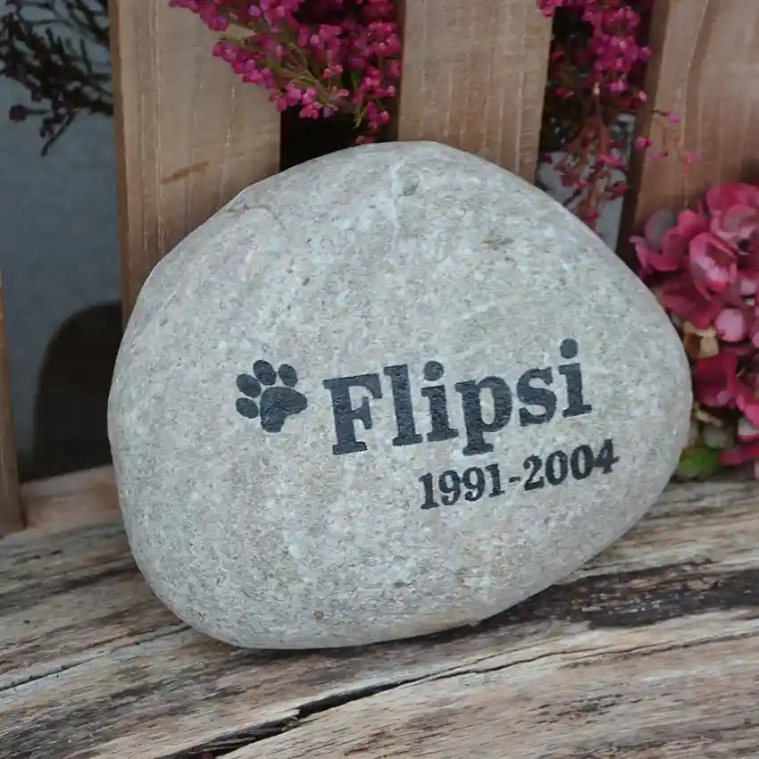 Musterbeispiel für einen Naturstein Findling als Tiergrab mit Namen des verstorbenen Hundes, Lebensdaten und einer Pfote als Symbol mit eingefärbter schwarzer Gravur