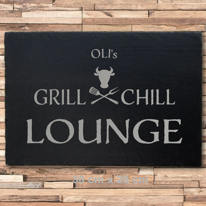 Deko Schieferplatte in der Größe 30 x 20 cm mit dem Motiv Grill und Chill Lounge, das auf die Schieferplatte in personalisierter Form mittels Laser graviert wird. Zwischen Grill und Chill sind gekreuzte Grillgabeln und ein stilisierter Bullenkopf.