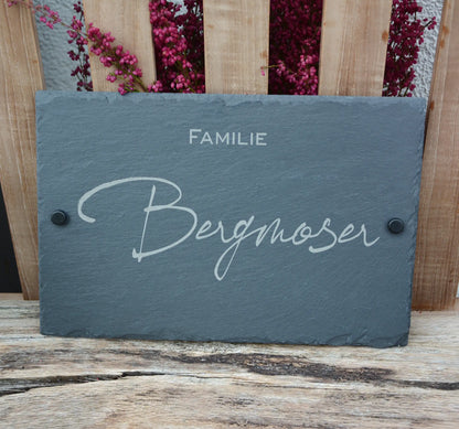 Tür- und Namensschild aus Schiefer mit schwungvoller Handschrift in personalisierter Form in der Größe 30 x 20 cm. Hier als Beispiel "Familie" in kleinerer Zeile unterhalb des Nachnamens und schwarzen Abstandshalter